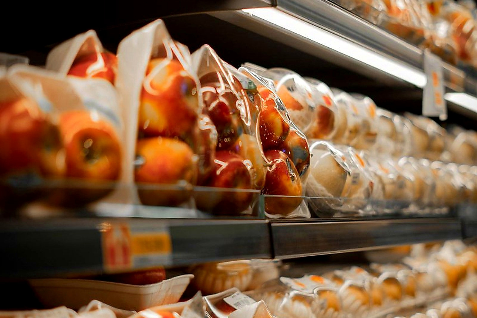 Free Packaged fresh apples displayed on a supermarket shelf with bright lighting. Stock Photo